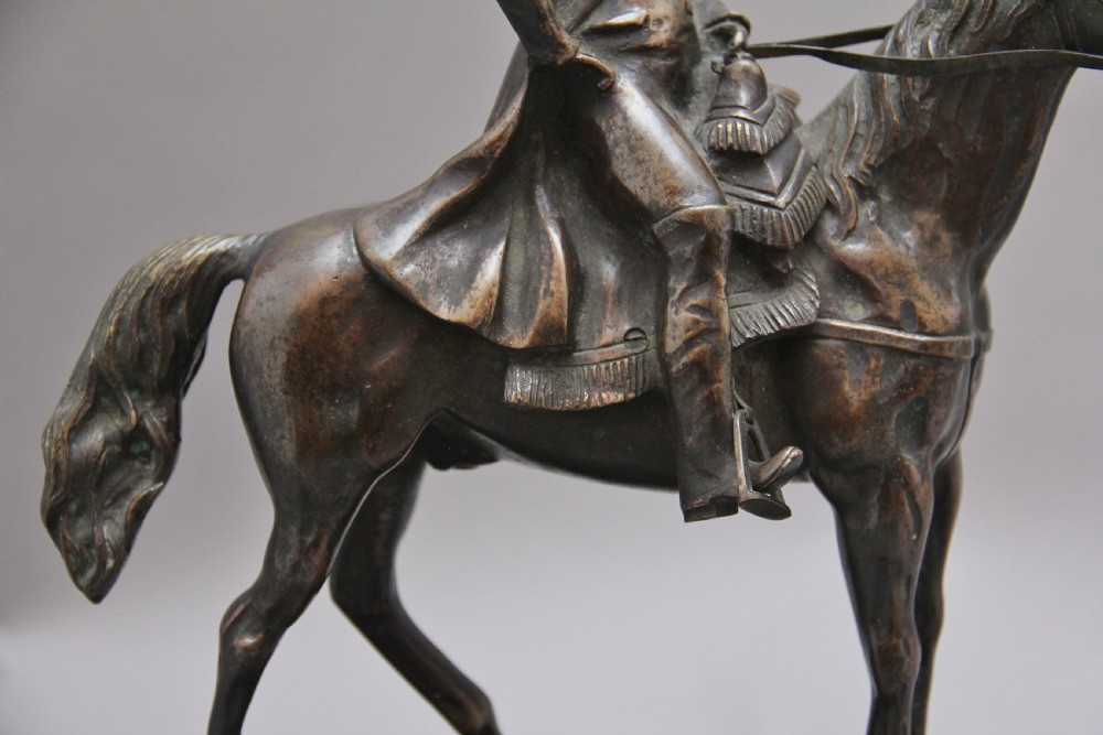 A dark bronze equestrian sculpture depicting Napoleon Bonaparte on horseback mounted on a stepped brass and black marble plinth. View IX