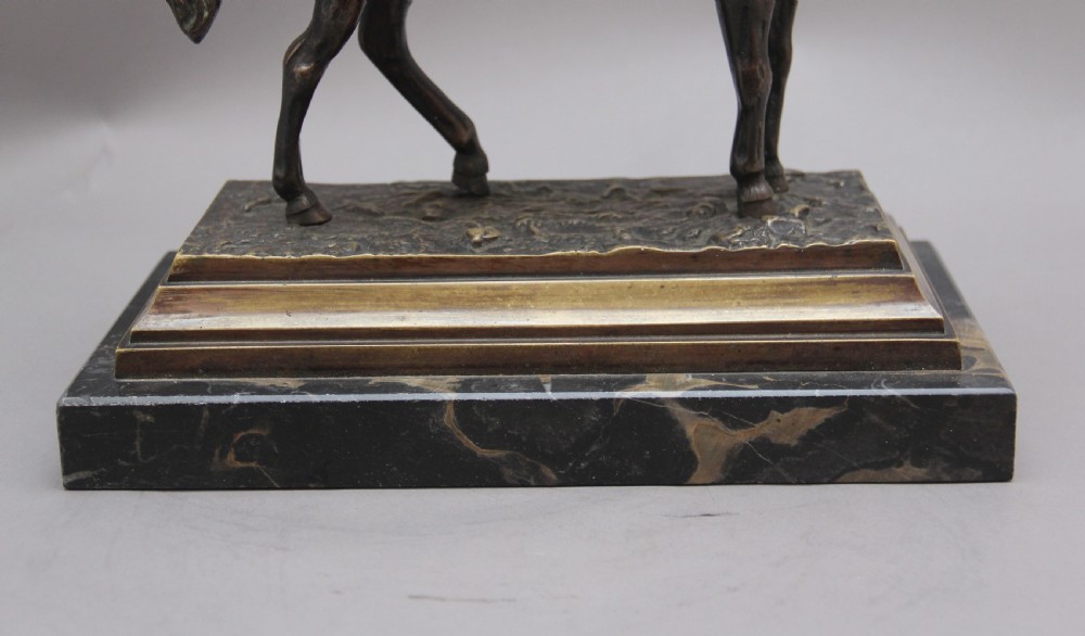 A dark bronze equestrian sculpture depicting Napoleon Bonaparte on horseback mounted on a stepped brass and black marble plinth. View X