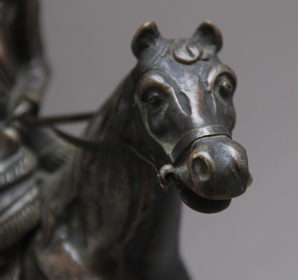 A dark bronze equestrian sculpture depicting Napoleon Bonaparte on horseback mounted on a stepped brass and black marble plinth. View XI