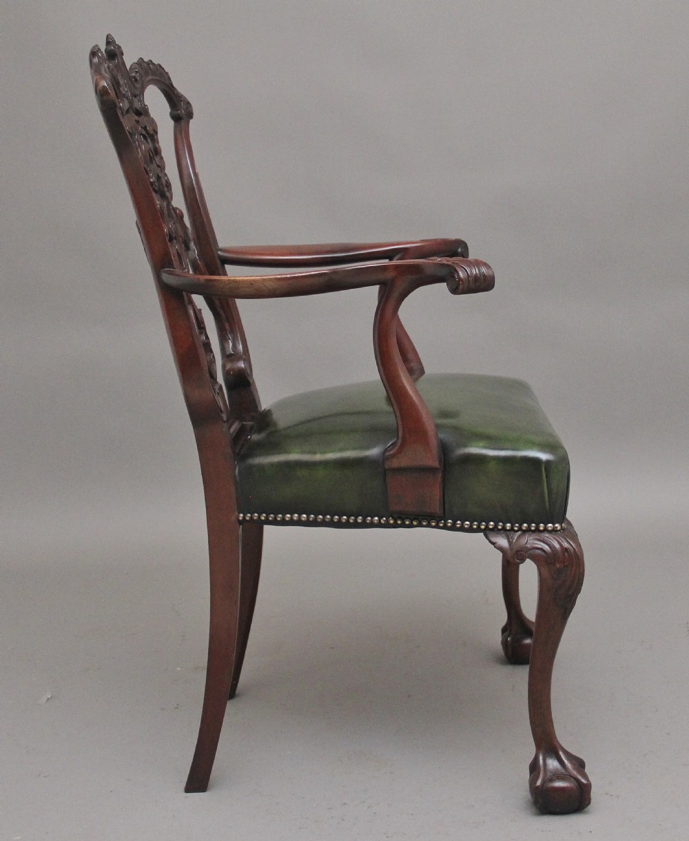 An early 20th-century Chippendale style mahogany armchair featuring a detailed pierced back splat, green leather upholstered seat with brass studding, curved armrests, and cabriole front legs terminating in claw and ball feet. View IV