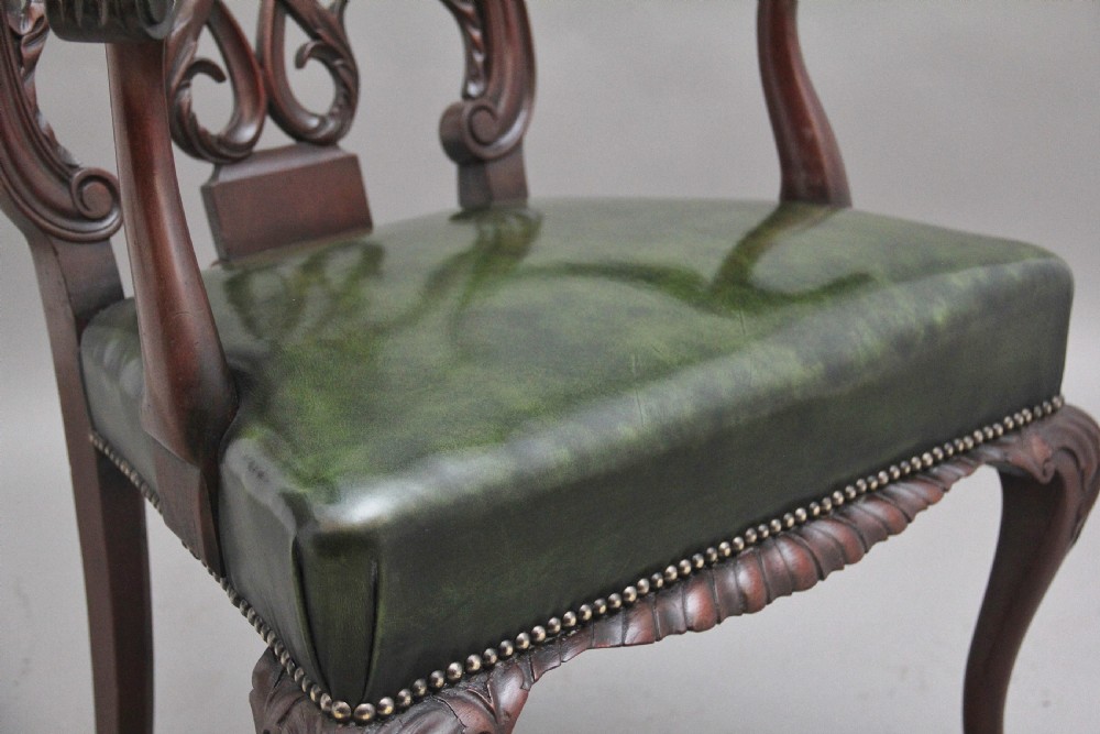 An early 20th-century Chippendale style mahogany armchair featuring a detailed pierced back splat, green leather upholstered seat with brass studding, curved armrests, and cabriole front legs terminating in claw and ball feet. View X