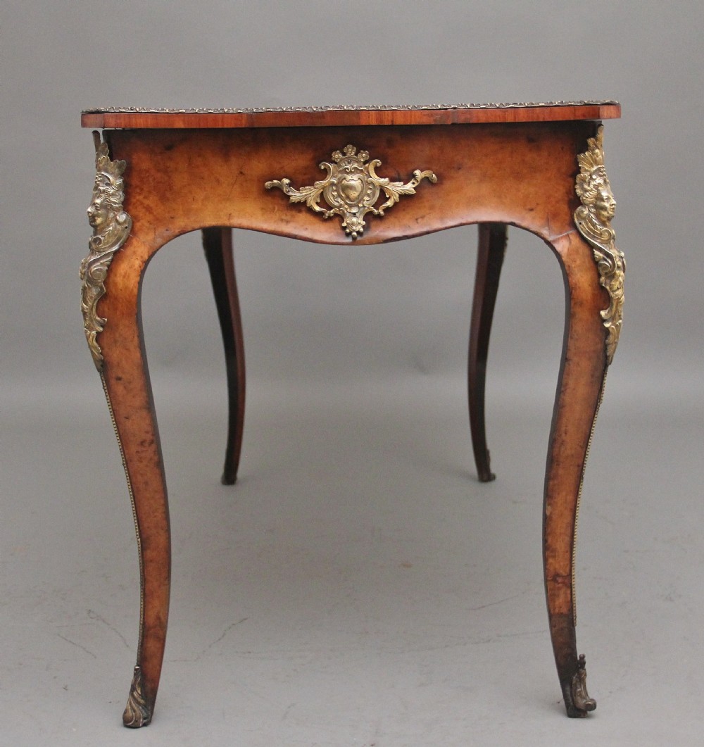 A 19th-century burr walnut bureau plat writing table with decorative gilt-bronze mounts, cabriole legs, and a dark leather inset top. View IV