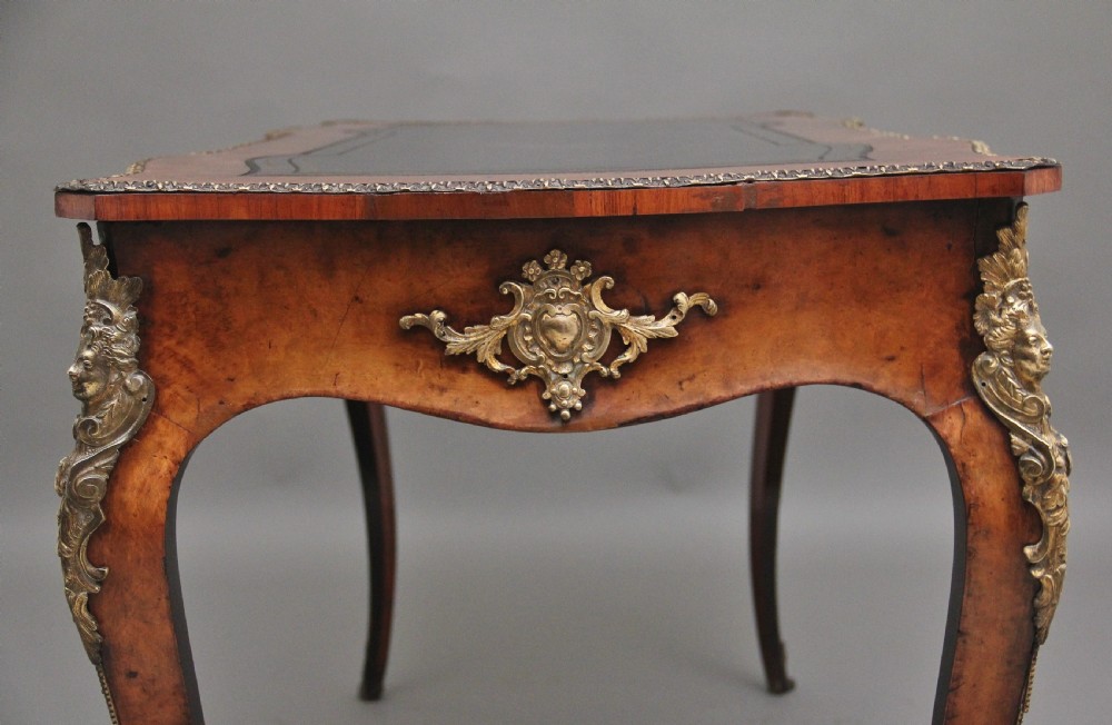 A 19th-century burr walnut bureau plat writing table with decorative gilt-bronze mounts, cabriole legs, and a dark leather inset top. View V