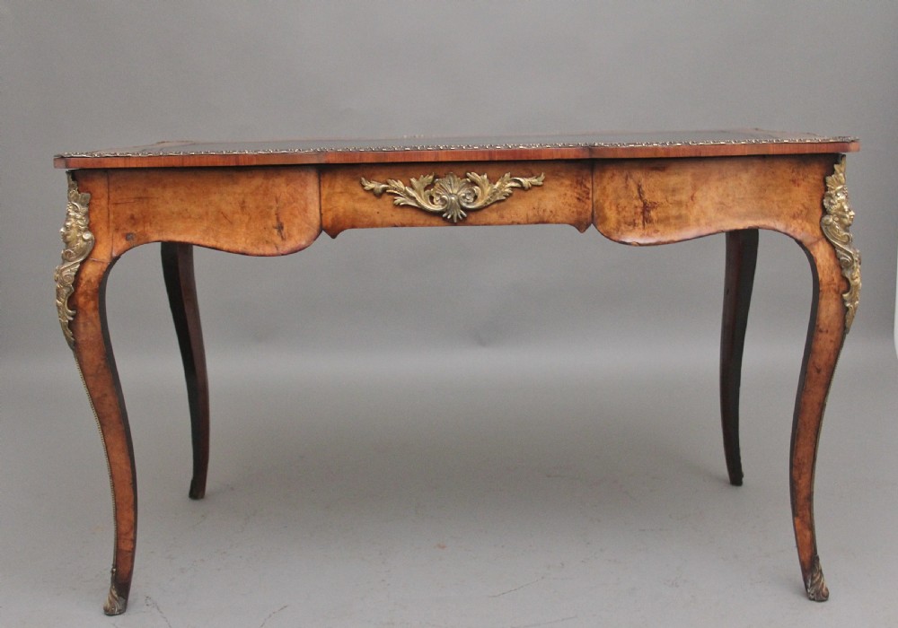A 19th-century burr walnut bureau plat writing table with decorative gilt-bronze mounts, cabriole legs, and a dark leather inset top. View VI