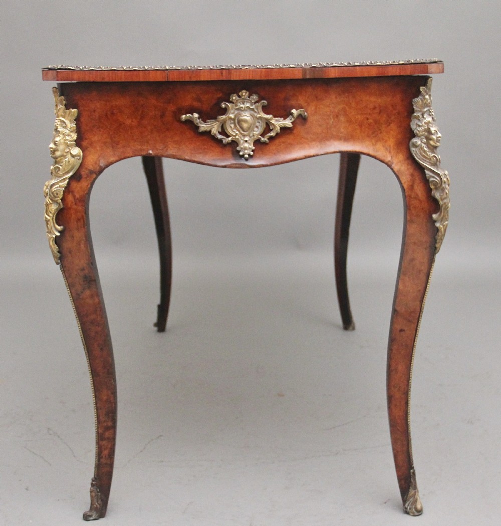 A 19th-century burr walnut bureau plat writing table with decorative gilt-bronze mounts, cabriole legs, and a dark leather inset top. View VII