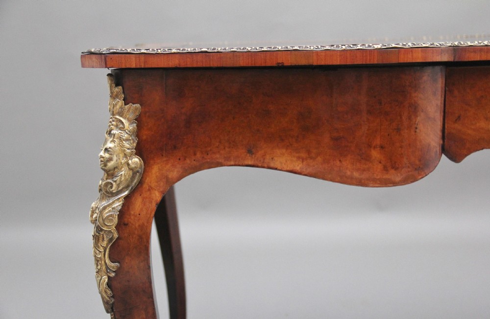 A 19th-century burr walnut bureau plat writing table with decorative gilt-bronze mounts, cabriole legs, and a dark leather inset top. View X