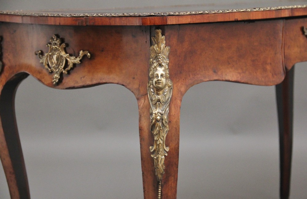 A 19th-century burr walnut bureau plat writing table with decorative gilt-bronze mounts, cabriole legs, and a dark leather inset top. View XII