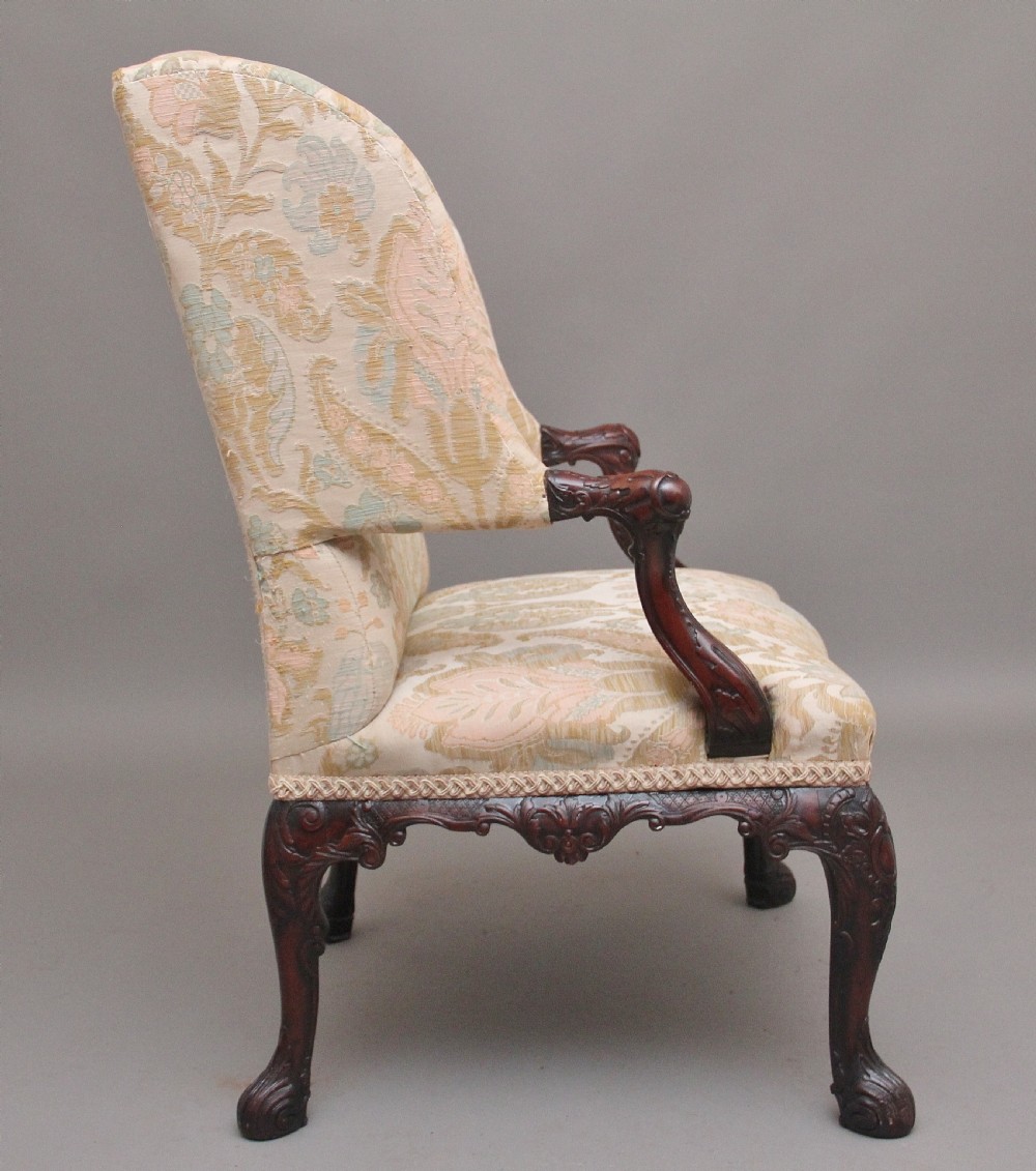 A 19th-century mahogany wingback armchair featuring carved cabriole legs, claw-and-ball feet, and patterned cream damask upholstery. View II