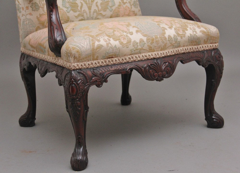 A 19th-century mahogany wingback armchair featuring carved cabriole legs, claw-and-ball feet, and patterned cream damask upholstery. View VI
