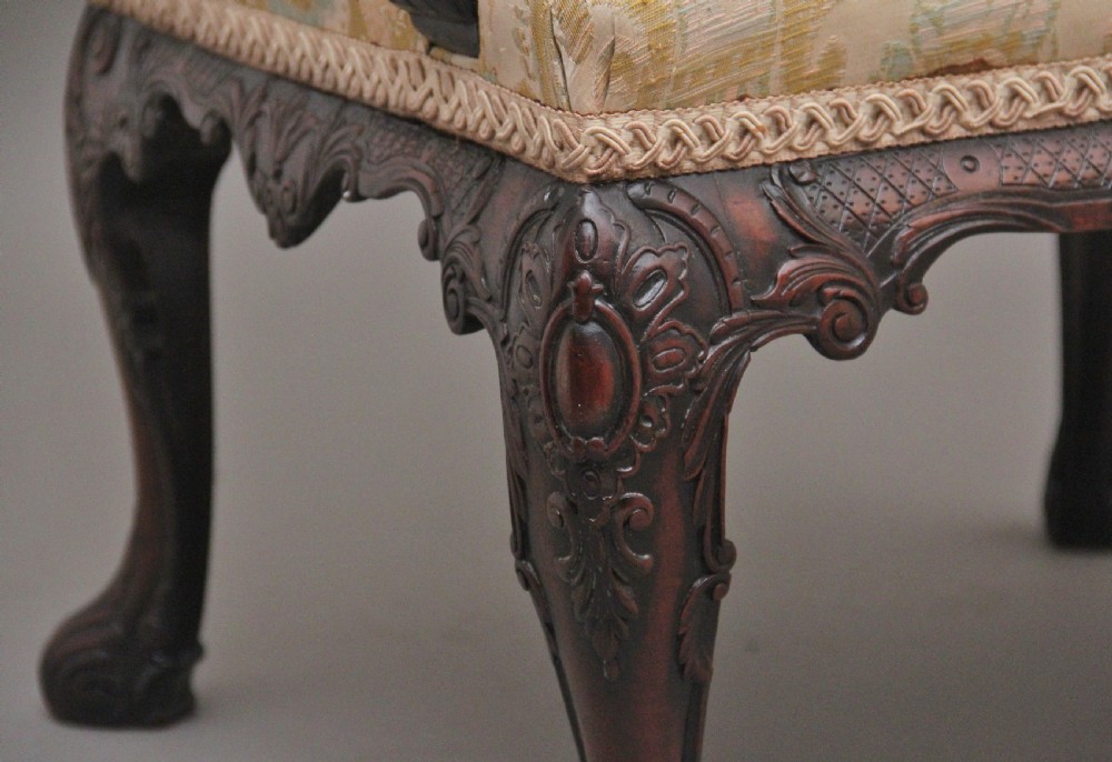 A 19th-century mahogany wingback armchair featuring carved cabriole legs, claw-and-ball feet, and patterned cream damask upholstery. View VII