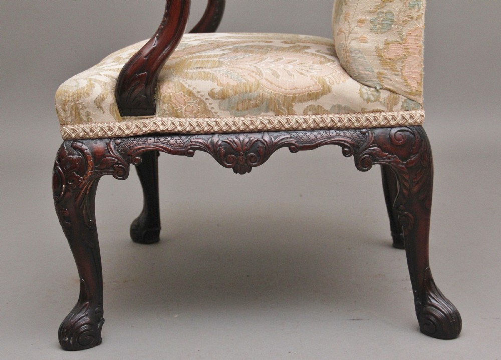 A 19th-century mahogany wingback armchair featuring carved cabriole legs, claw-and-ball feet, and patterned cream damask upholstery. View VIII