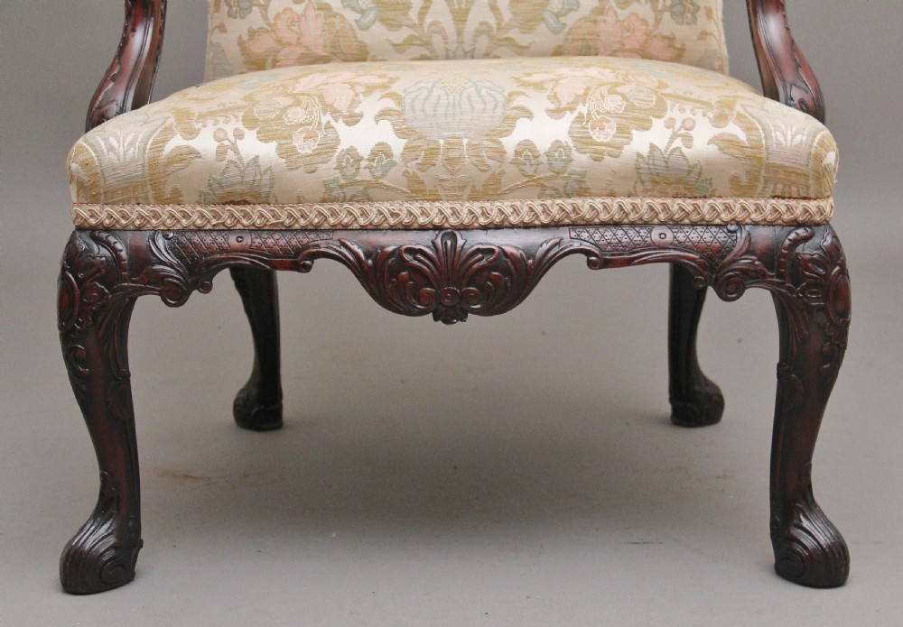 A 19th-century mahogany wingback armchair featuring carved cabriole legs, claw-and-ball feet, and patterned cream damask upholstery. View IX
