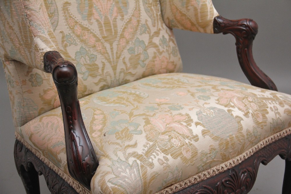 A 19th-century mahogany wingback armchair featuring carved cabriole legs, claw-and-ball feet, and patterned cream damask upholstery. View X