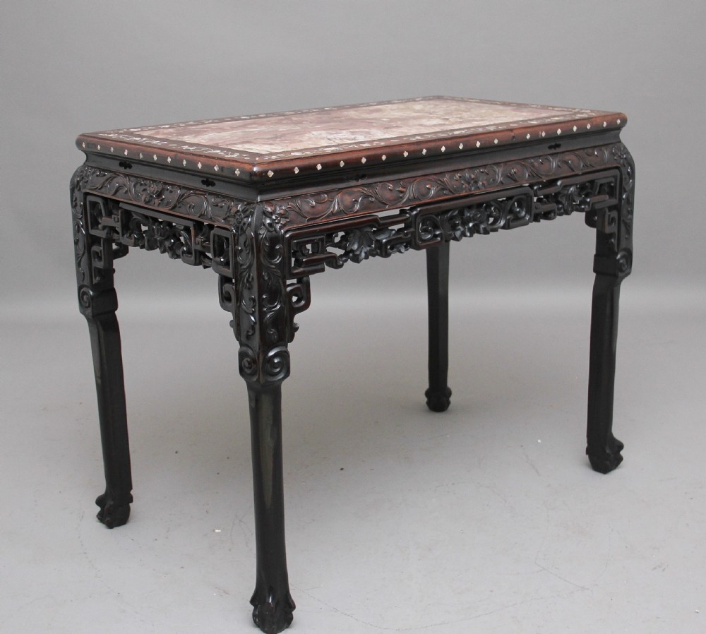 A dark carved hardwood Chinese centre table with an inset marble top and mother-of-pearl inlay along the frame.