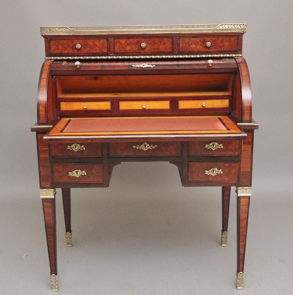 A 19th-century French kingwood cylinder desk featuring parquetry veneering, gilt-brass mounts, tapered square legs, and a curved roll-top section over multiple small drawers. View II