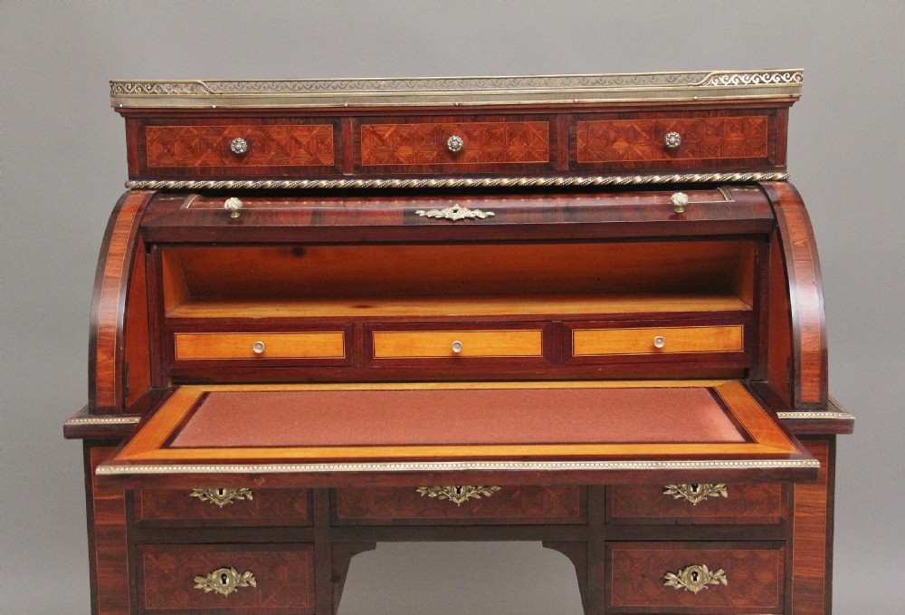 A 19th-century French kingwood cylinder desk featuring parquetry veneering, gilt-brass mounts, tapered square legs, and a curved roll-top section over multiple small drawers. View IV
