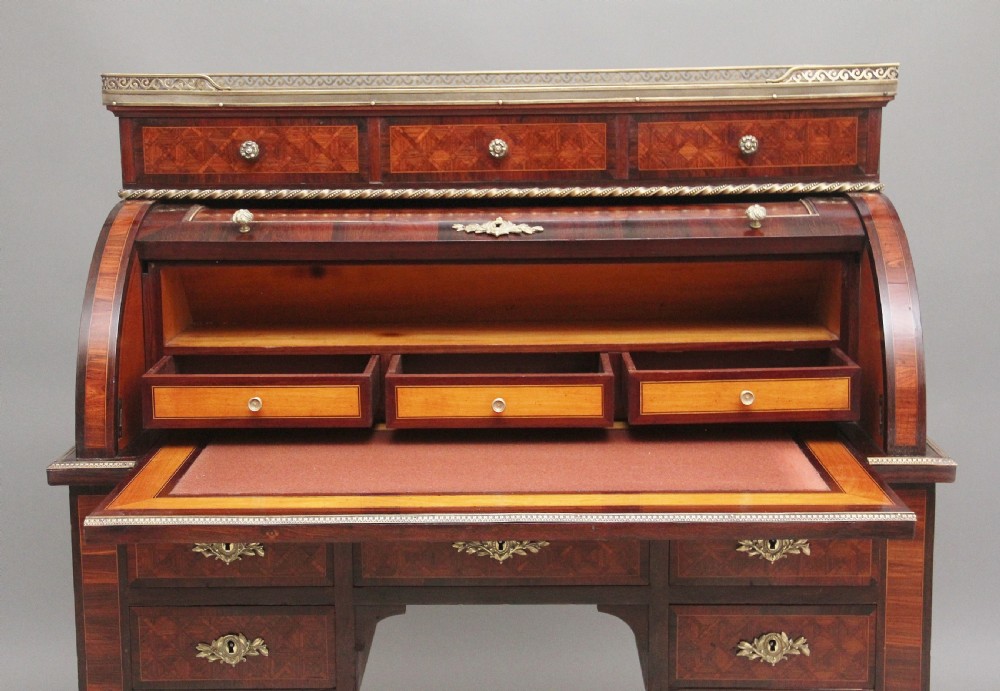 A 19th-century French kingwood cylinder desk featuring parquetry veneering, gilt-brass mounts, tapered square legs, and a curved roll-top section over multiple small drawers. View V