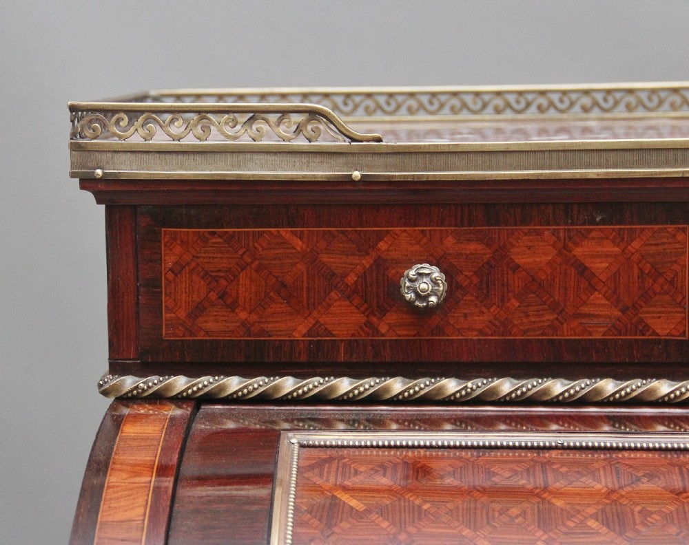 A 19th-century French kingwood cylinder desk featuring parquetry veneering, gilt-brass mounts, tapered square legs, and a curved roll-top section over multiple small drawers. View VIII