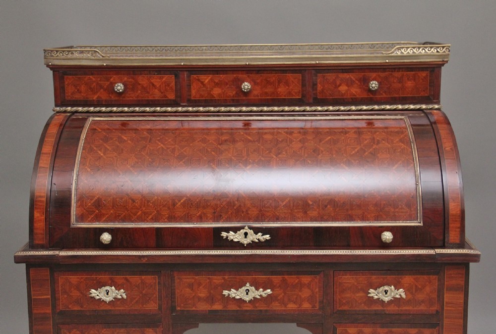A 19th-century French kingwood cylinder desk featuring parquetry veneering, gilt-brass mounts, tapered square legs, and a curved roll-top section over multiple small drawers. View XI