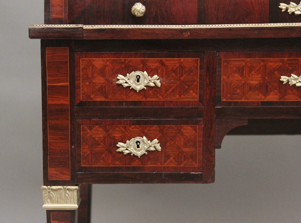 A 19th-century French kingwood cylinder desk featuring parquetry veneering, gilt-brass mounts, tapered square legs, and a curved roll-top section over multiple small drawers. View XIV