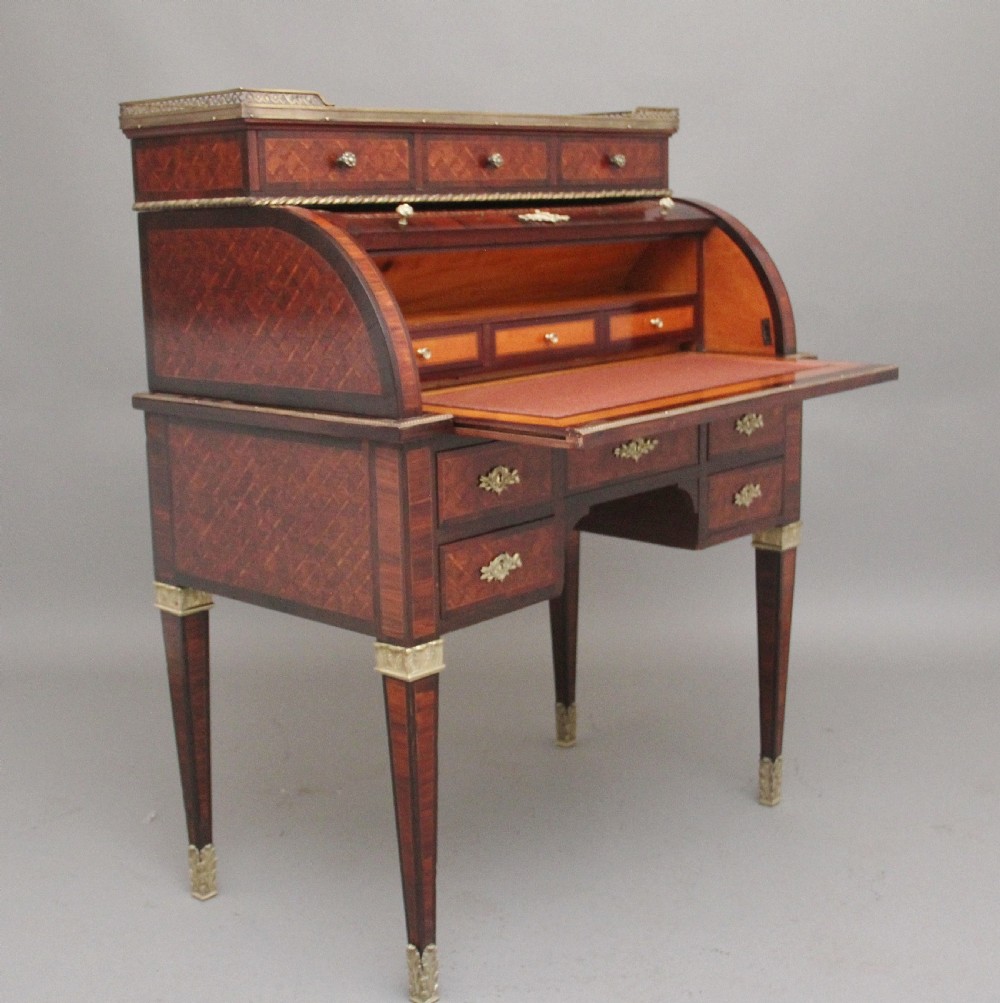 A 19th-century French kingwood cylinder desk featuring parquetry veneering, gilt-brass mounts, tapered square legs, and a curved roll-top section over multiple small drawers. View XVII