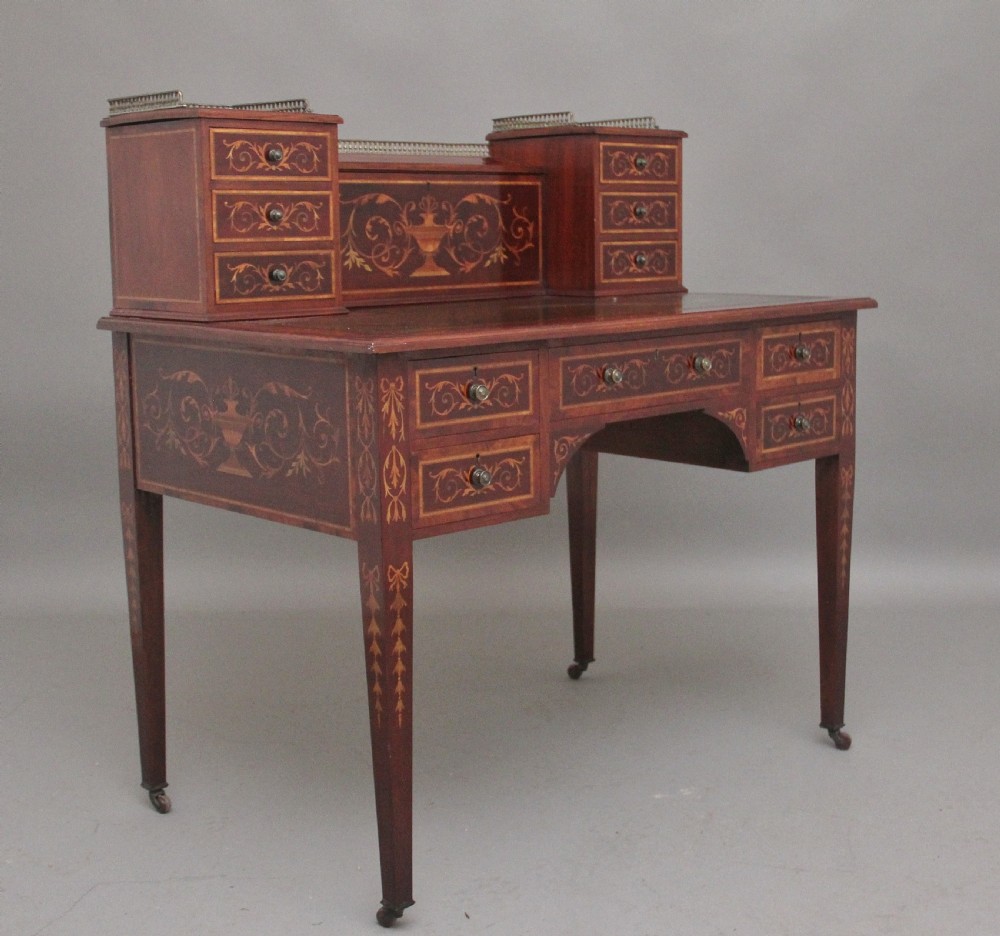 A 19th-century mahogany writing desk featuring intricate floral marquetry inlays, a raised gallery with drawers, square tapered legs, and brass castors. View II