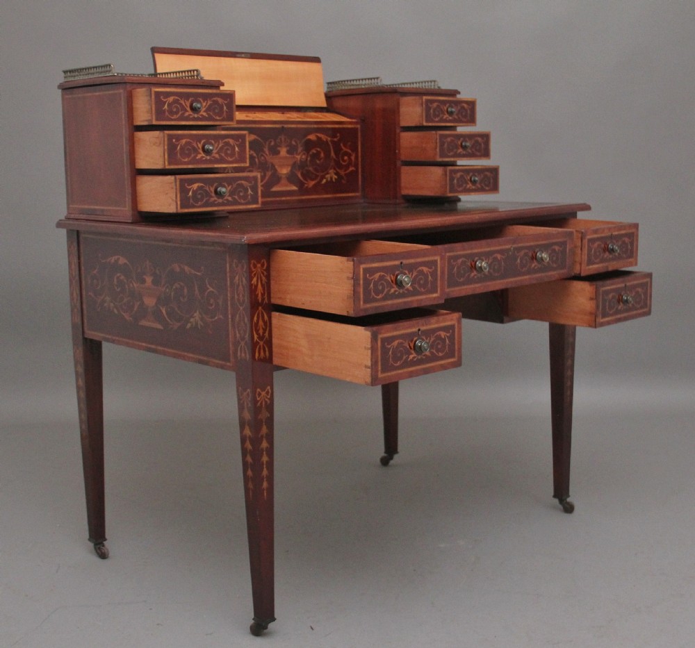 A 19th-century mahogany writing desk featuring intricate floral marquetry inlays, a raised gallery with drawers, square tapered legs, and brass castors. View III