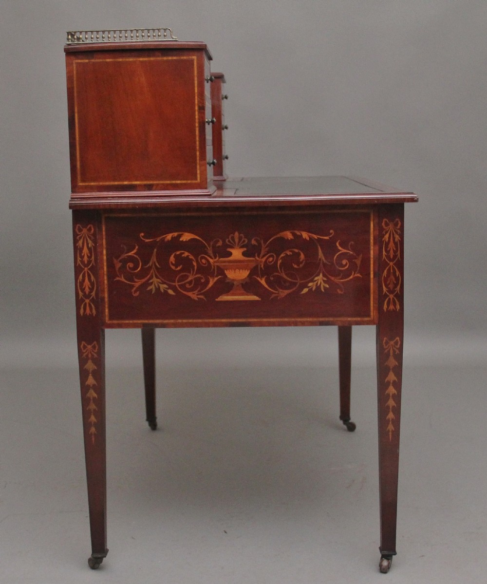 A 19th-century mahogany writing desk featuring intricate floral marquetry inlays, a raised gallery with drawers, square tapered legs, and brass castors. View IV