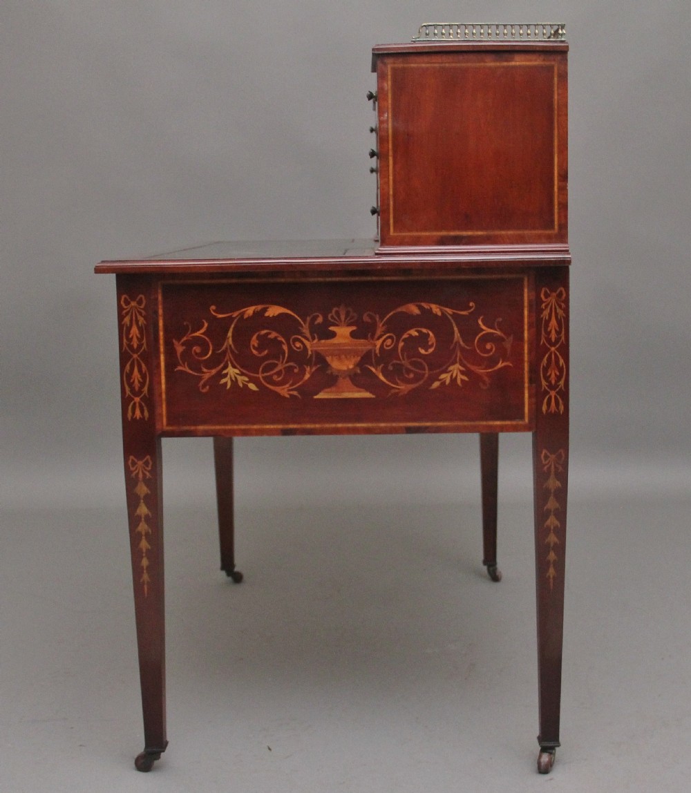 A 19th-century mahogany writing desk featuring intricate floral marquetry inlays, a raised gallery with drawers, square tapered legs, and brass castors. View VII