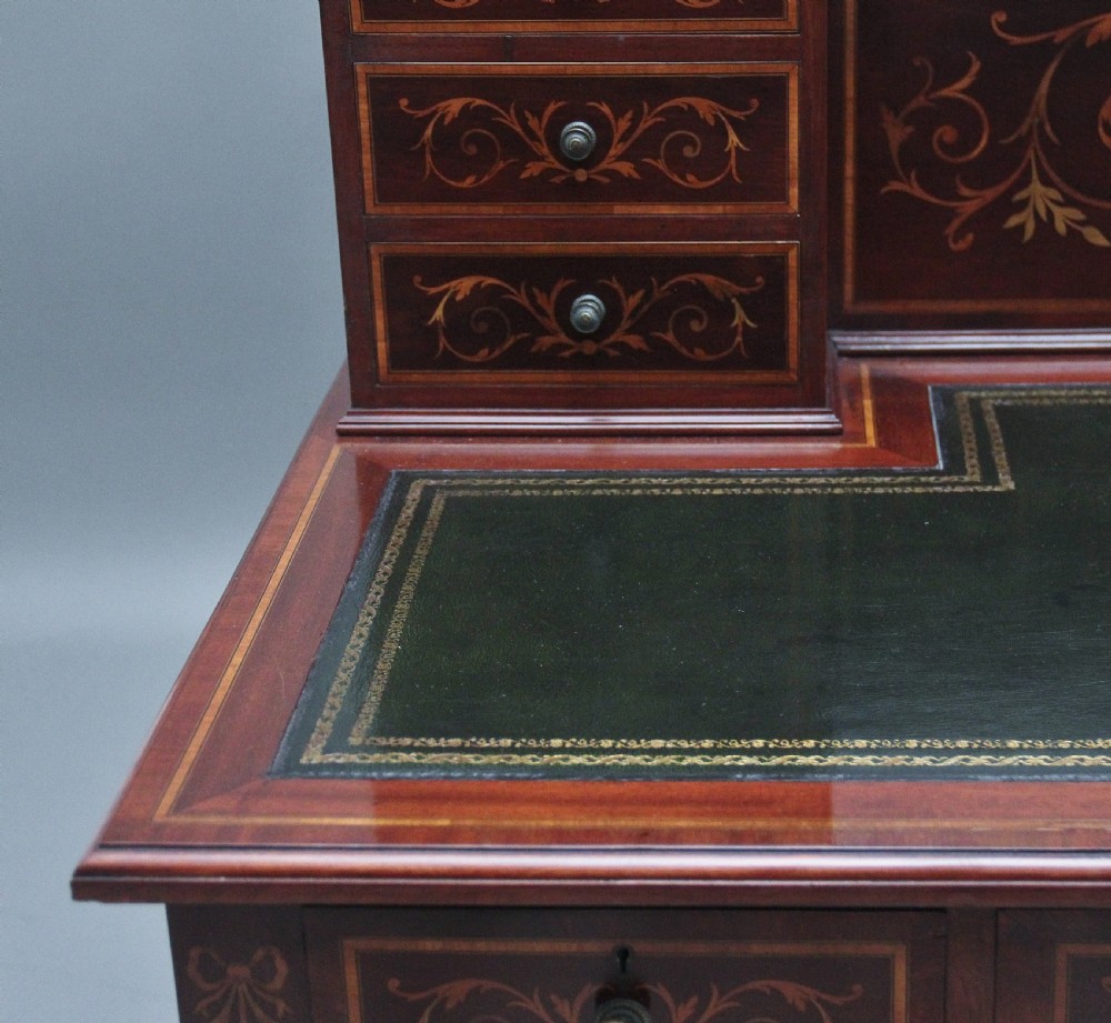 A 19th-century mahogany writing desk featuring intricate floral marquetry inlays, a raised gallery with drawers, square tapered legs, and brass castors. View IX