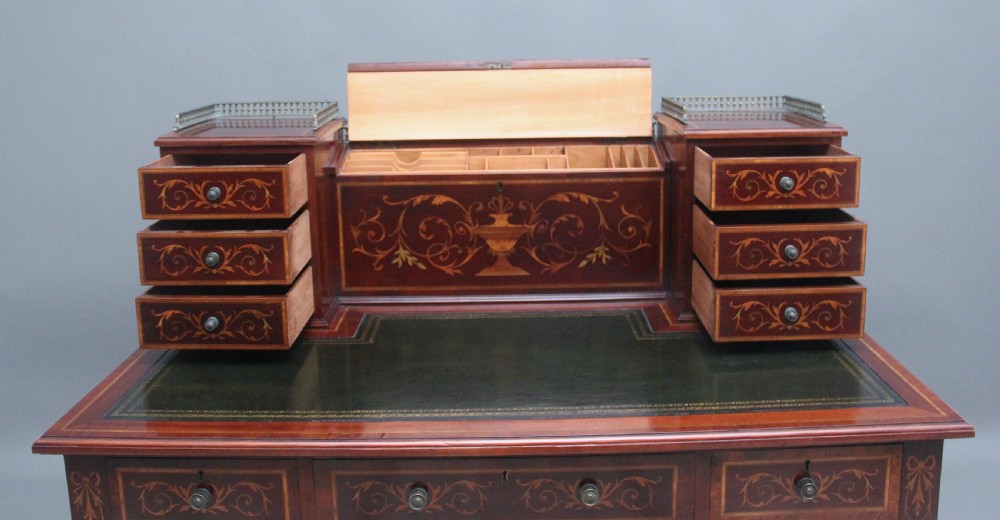 A 19th-century mahogany writing desk featuring intricate floral marquetry inlays, a raised gallery with drawers, square tapered legs, and brass castors. View X