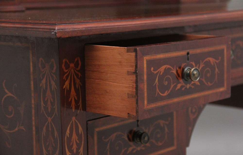 A 19th-century mahogany writing desk featuring intricate floral marquetry inlays, a raised gallery with drawers, square tapered legs, and brass castors. View XVI