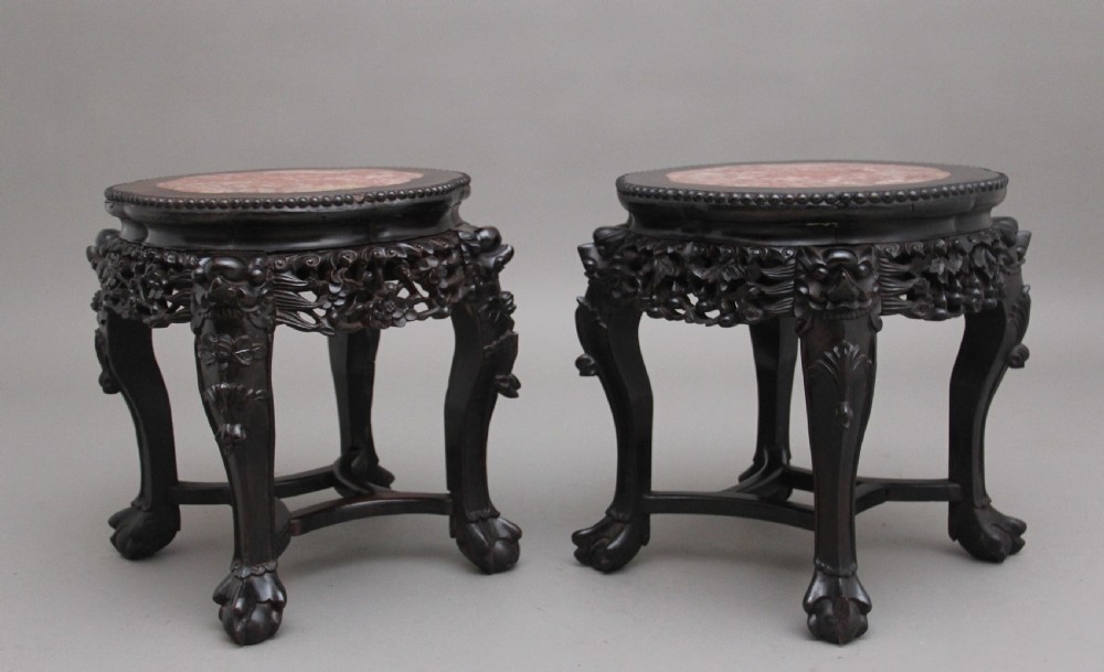 A pair of 19th-century Chinese dark hardwood low stands featuring carved pierced aprons, cabriole legs with claw feet, and round pink marble tops. View III