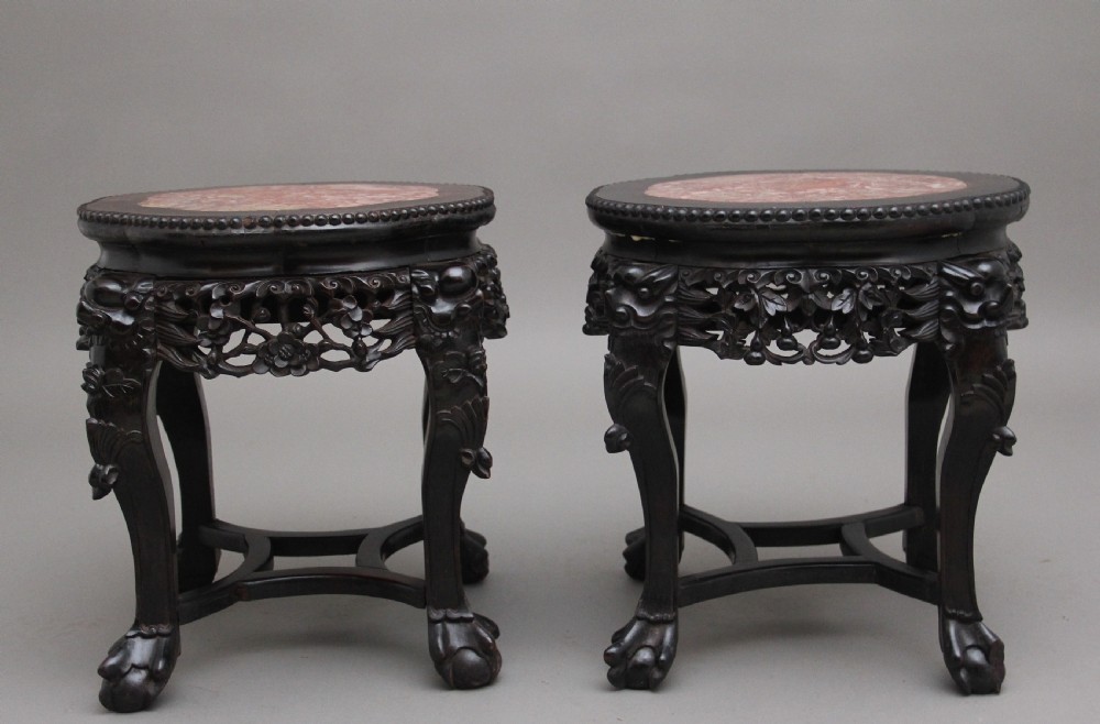 A pair of 19th-century Chinese dark hardwood low stands featuring carved pierced aprons, cabriole legs with claw feet, and round pink marble tops. View IV
