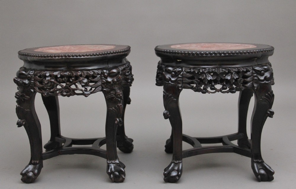 A pair of 19th-century Chinese dark hardwood low stands featuring carved pierced aprons, cabriole legs with claw feet, and round pink marble tops. View VI