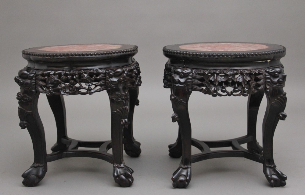 A pair of 19th-century Chinese dark hardwood low stands featuring carved pierced aprons, cabriole legs with claw feet, and round pink marble tops. View VII
