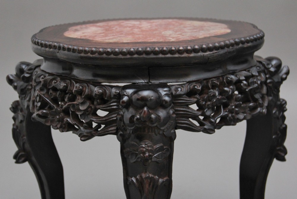 A pair of 19th-century Chinese dark hardwood low stands featuring carved pierced aprons, cabriole legs with claw feet, and round pink marble tops. View IX