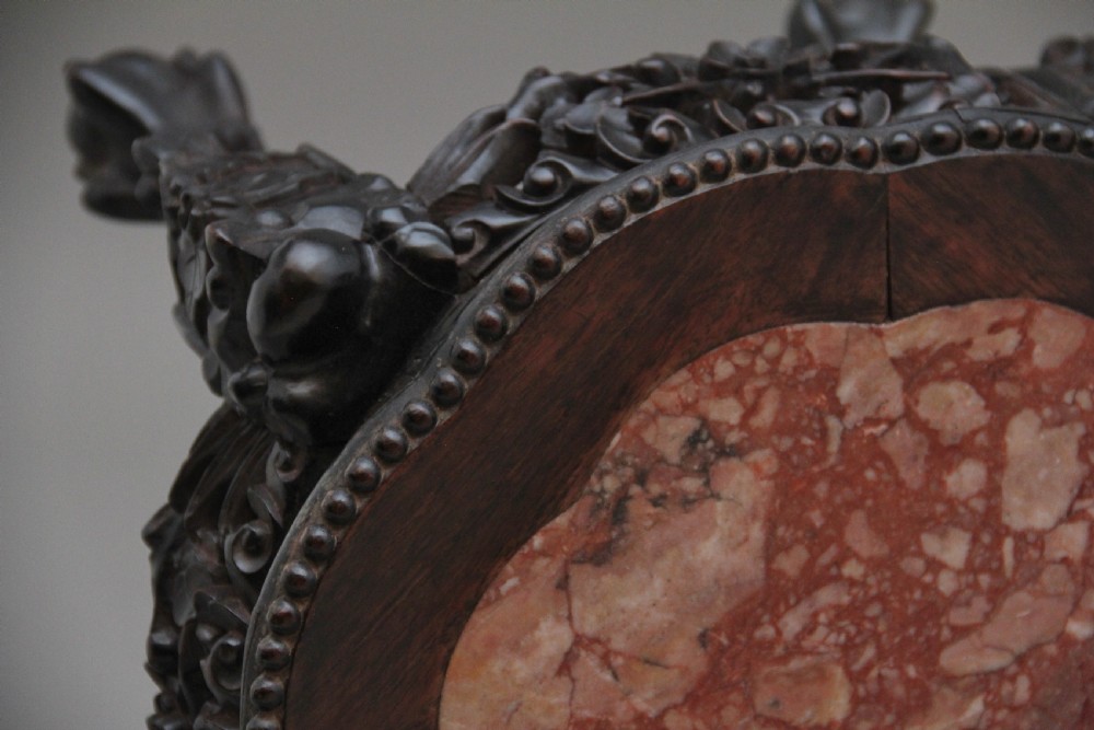 A pair of 19th-century Chinese dark hardwood low stands featuring carved pierced aprons, cabriole legs with claw feet, and round pink marble tops. View X