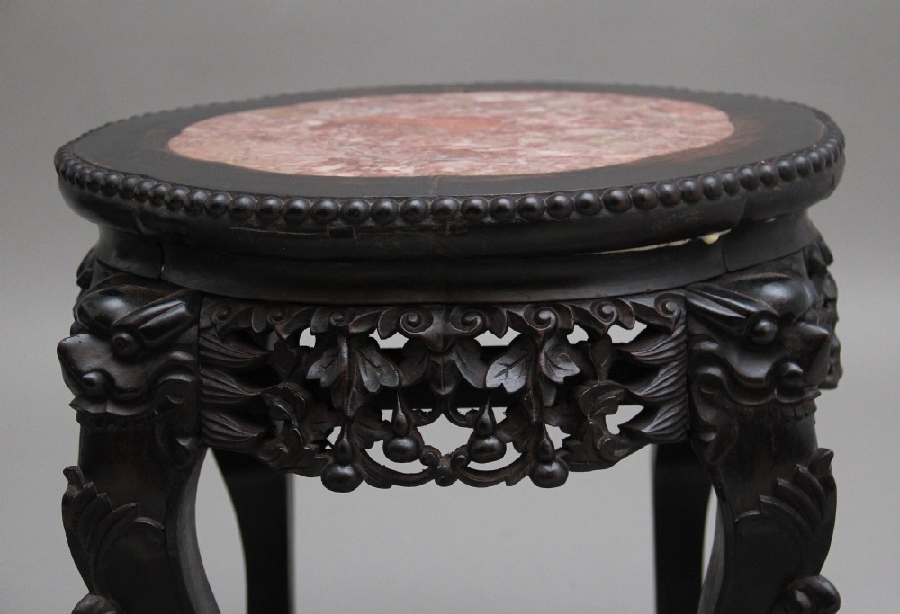 A pair of 19th-century Chinese dark hardwood low stands featuring carved pierced aprons, cabriole legs with claw feet, and round pink marble tops. View XI