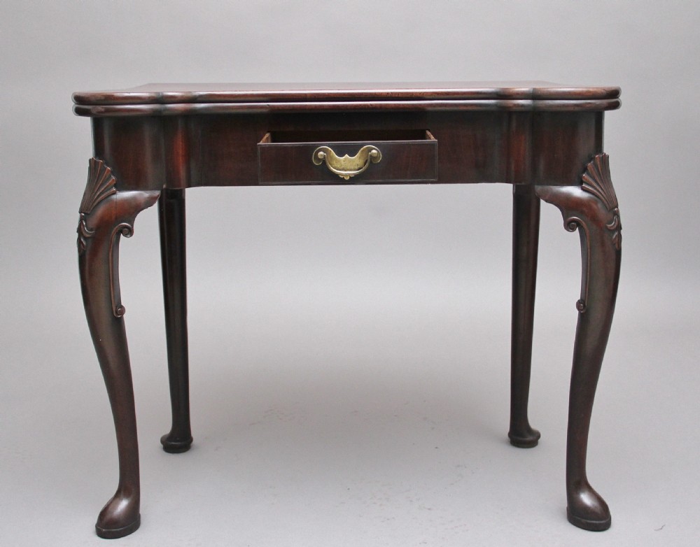 An 18th-century dark mahogany games table with a fold-over top, shell-carved cabriole legs, pad feet, and a central drawer. View II