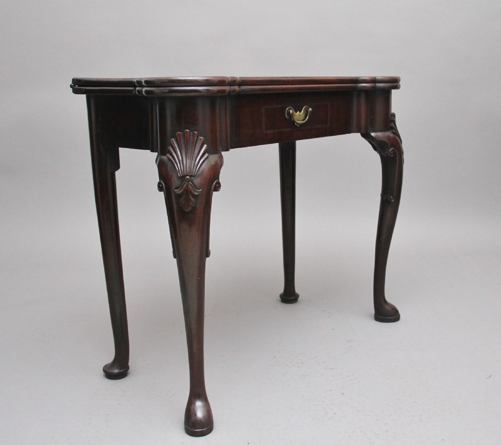 An 18th-century dark mahogany games table with a fold-over top, shell-carved cabriole legs, pad feet, and a central drawer. View IV