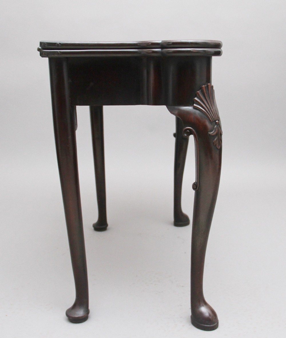 An 18th-century dark mahogany games table with a fold-over top, shell-carved cabriole legs, pad feet, and a central drawer. View VII