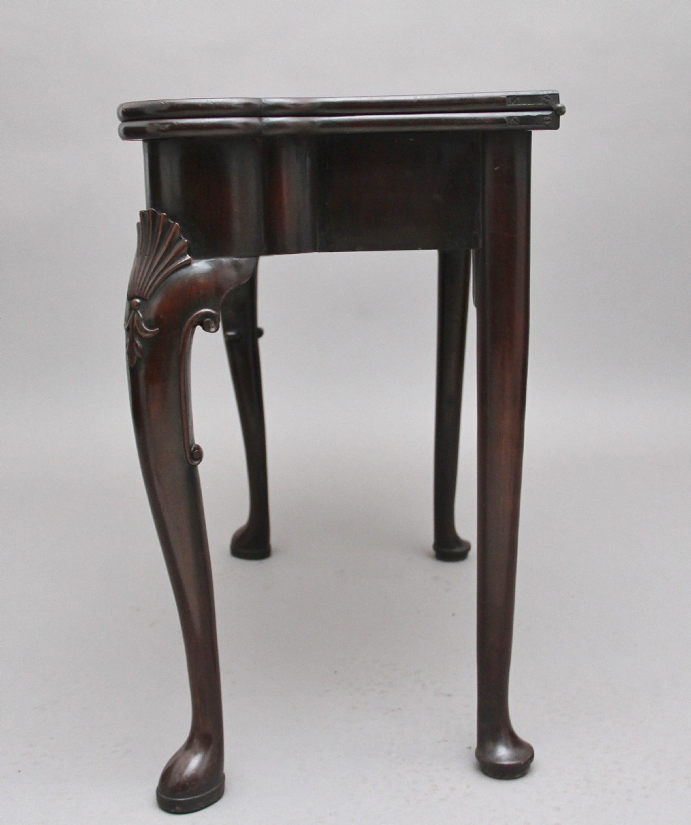 An 18th-century dark mahogany games table with a fold-over top, shell-carved cabriole legs, pad feet, and a central drawer. View IX