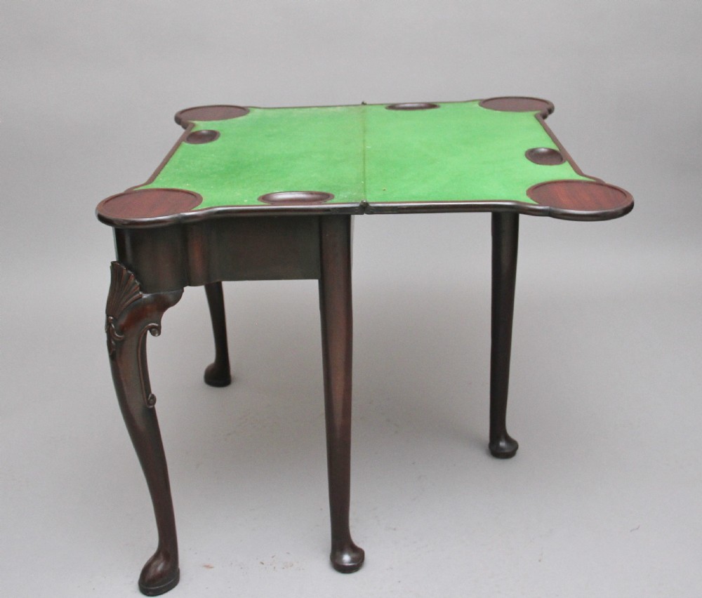 An 18th-century dark mahogany games table with a fold-over top, shell-carved cabriole legs, pad feet, and a central drawer. View XII