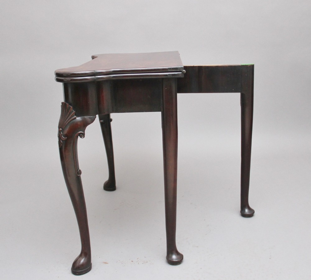 An 18th-century dark mahogany games table with a fold-over top, shell-carved cabriole legs, pad feet, and a central drawer. View XIV