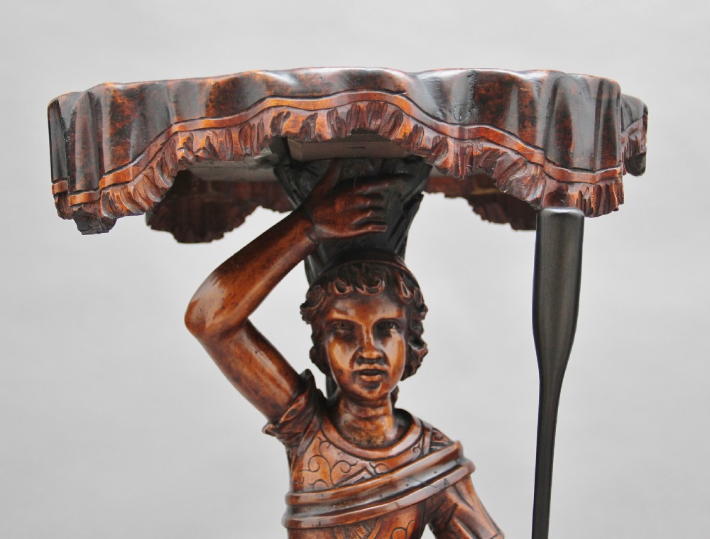 A dark carved wood Venetian figure stand featuring a gondolier holding an oar on a gondola hull, supporting a fringed draped tray surface. View VIII