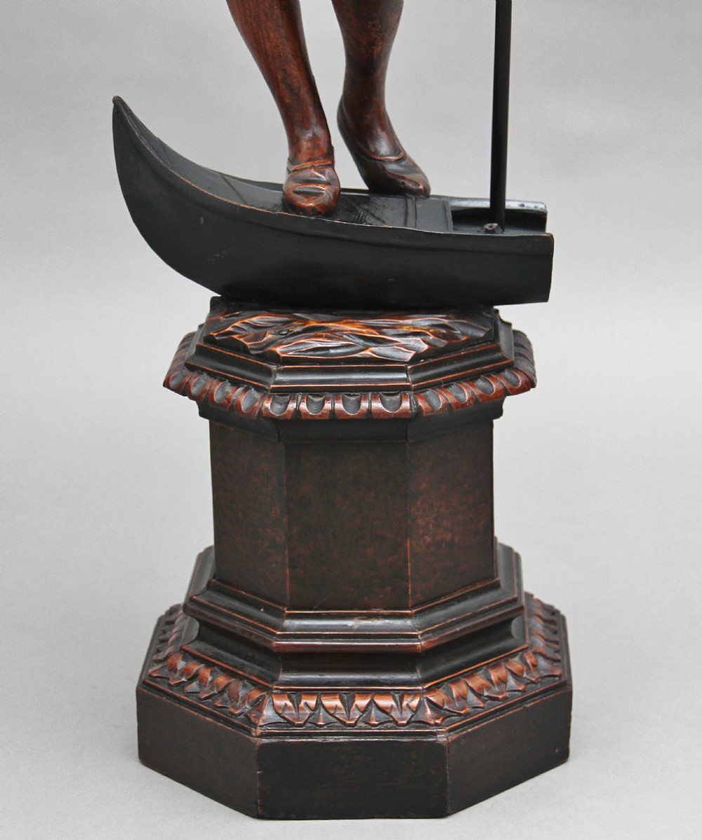 A dark carved wood Venetian figure stand featuring a gondolier holding an oar on a gondola hull, supporting a fringed draped tray surface. View XI