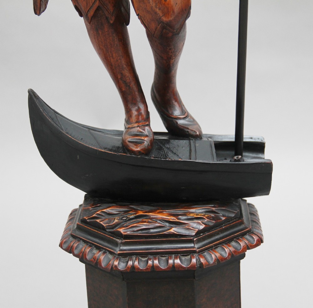 A dark carved wood Venetian figure stand featuring a gondolier holding an oar on a gondola hull, supporting a fringed draped tray surface. View XII