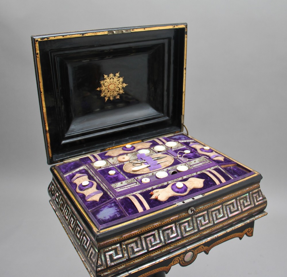 A nineteenth-century black lacquered papier-mache work table featuring mother-of-pearl Greek key inlay, hand-gilded detailing, a hinged box top, and a pedestal base on castors. View III