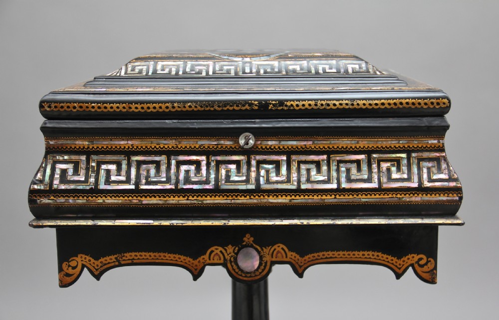 A nineteenth-century black lacquered papier-mache work table featuring mother-of-pearl Greek key inlay, hand-gilded detailing, a hinged box top, and a pedestal base on castors. View X